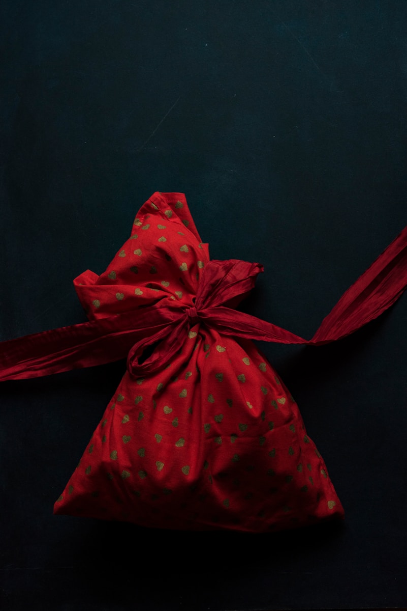 red and gold polka-dot drawstring pack on black surface